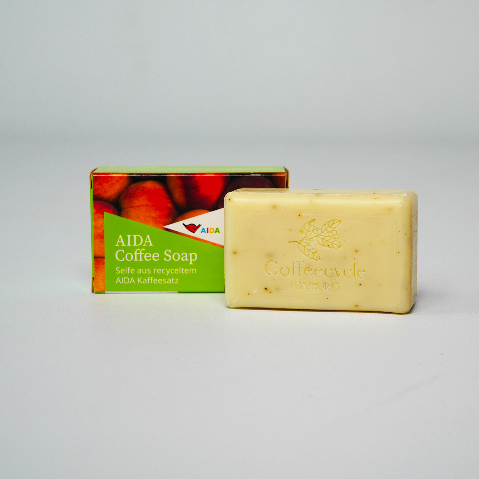 Rechteckiger Seifenblock mit marmorierter Oberfläche in Creme- und Rosatönen, Verpackung mit pinker Grafik und Pfirsichmotiv – Kaffeeseife Pfirsich.